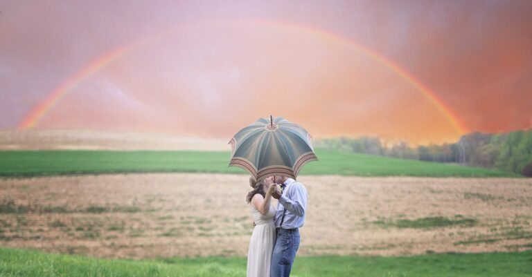 Photo of Couple Holding Umbrella While Kissing