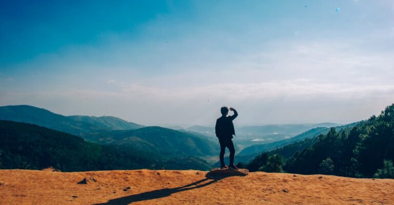 Silhouette of Man Standing on Mountain Cliff