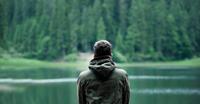 Photo of Man Wearing Hooded Jacket in Front of Body of Water