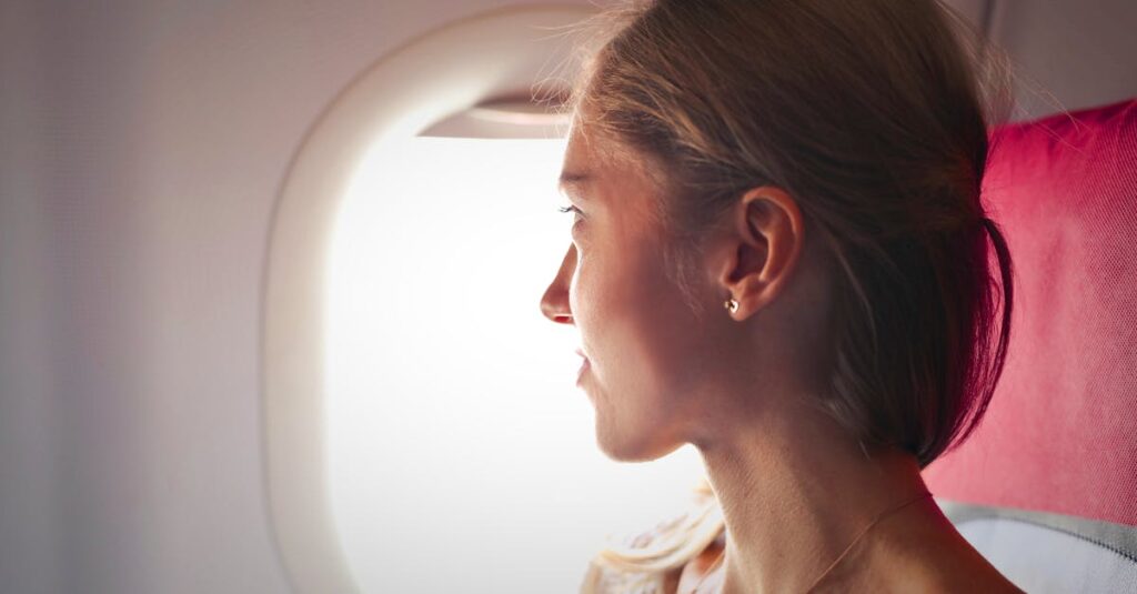 Selective Focus Photo of Woman Sitting on Chair Looking Outside Window on Plane