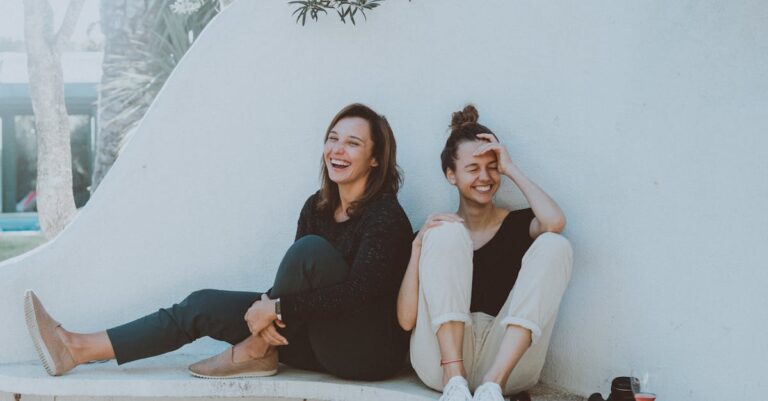 Two Women Sitting on White Bench