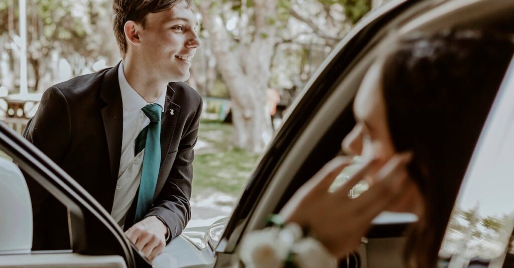 A Young Man in a Suit Standing by the Door of a Car and Woman Sitting Inside the Car