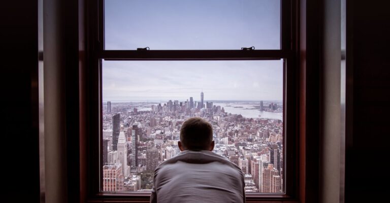 Man in Gray Shirt Looking at City Buildings