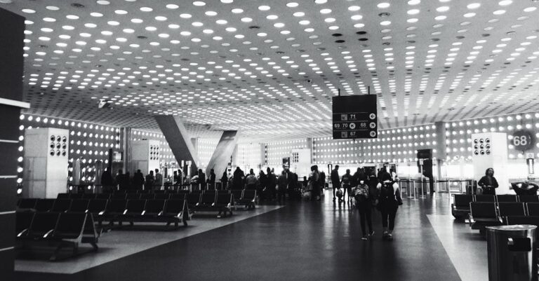 Grayscale Photography of People Walking on Concrete Pavement Hallway