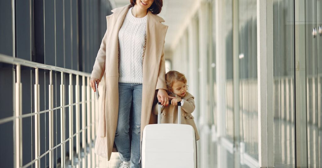 Positive mother and daughter with suitcase in airport corridor