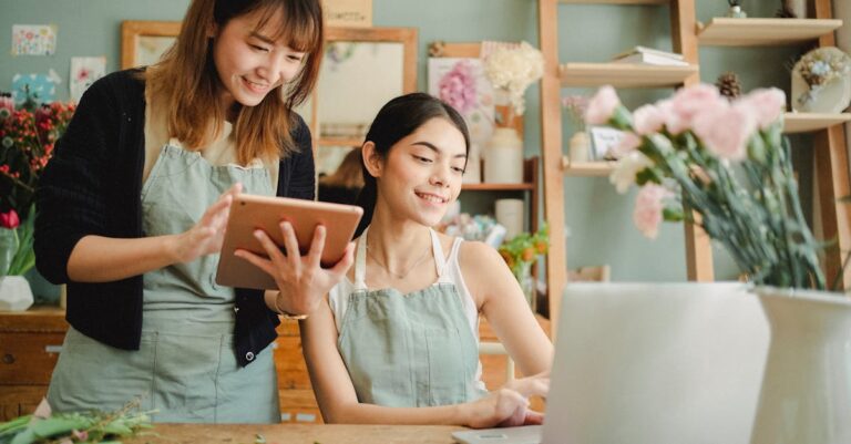 Happy multiracial women working on gadgets in floral store