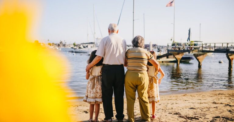 Grandparents With Their Granddaughters Standing By The Shore