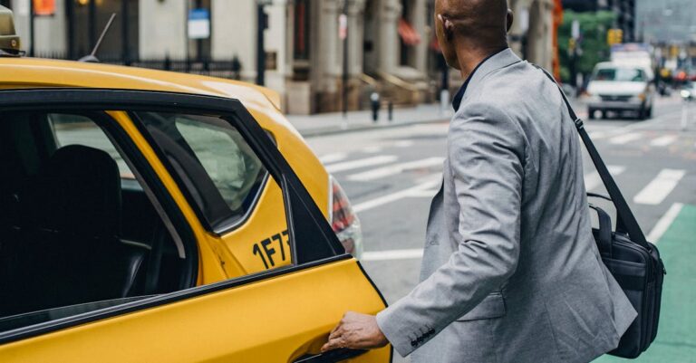 Faceless black man opening taxi door on busy street