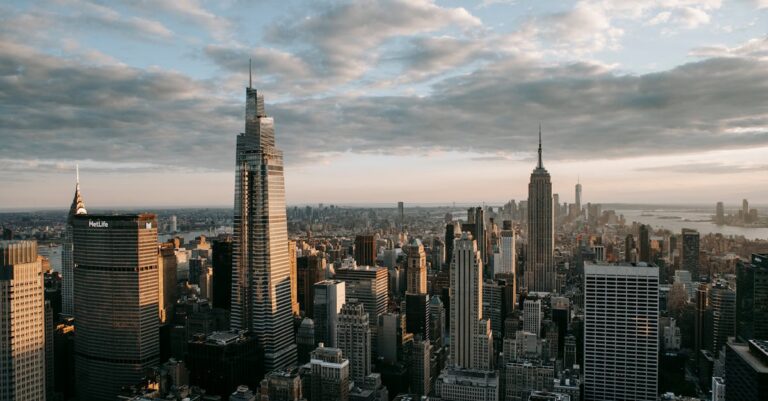 Multistage building facades with spires against ocean under cloudy sky in United States of America