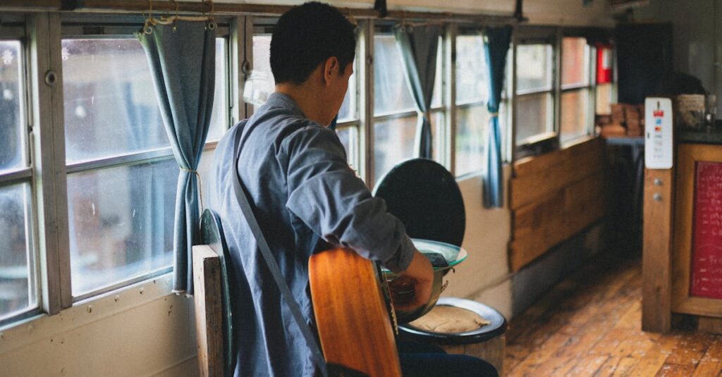 A man plays an acoustic guitar inside a converted bus with rustic interior design.