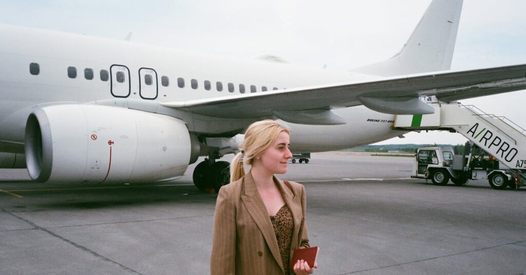 A stylish young woman holding a passport stands by an airplane on the tarmac.