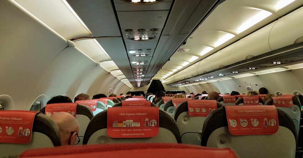 A look inside an airplane cabin filled with seated passengers during a flight.