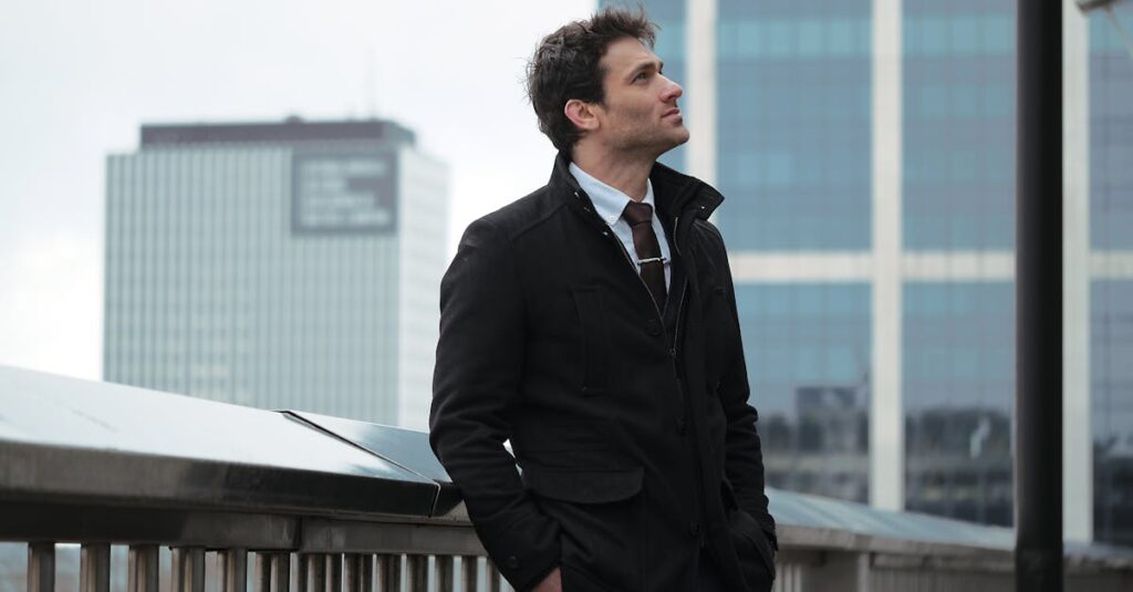 Man standing on a city bridge with skyscrapers in the background, exuding urban style.