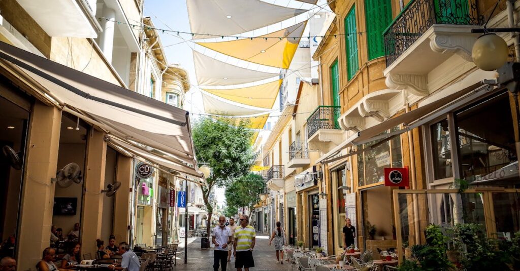 Bustling street in Nicosia, Cyprus with cafes, shops, and people under colorful shades.