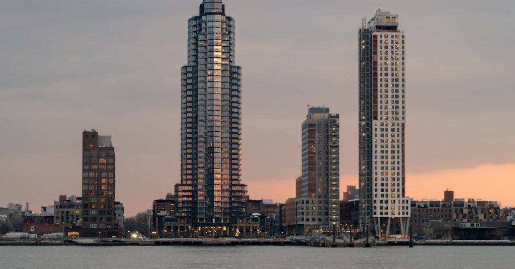 A tranquil view of New York City skyscrapers at sunset with reflections on the East River.