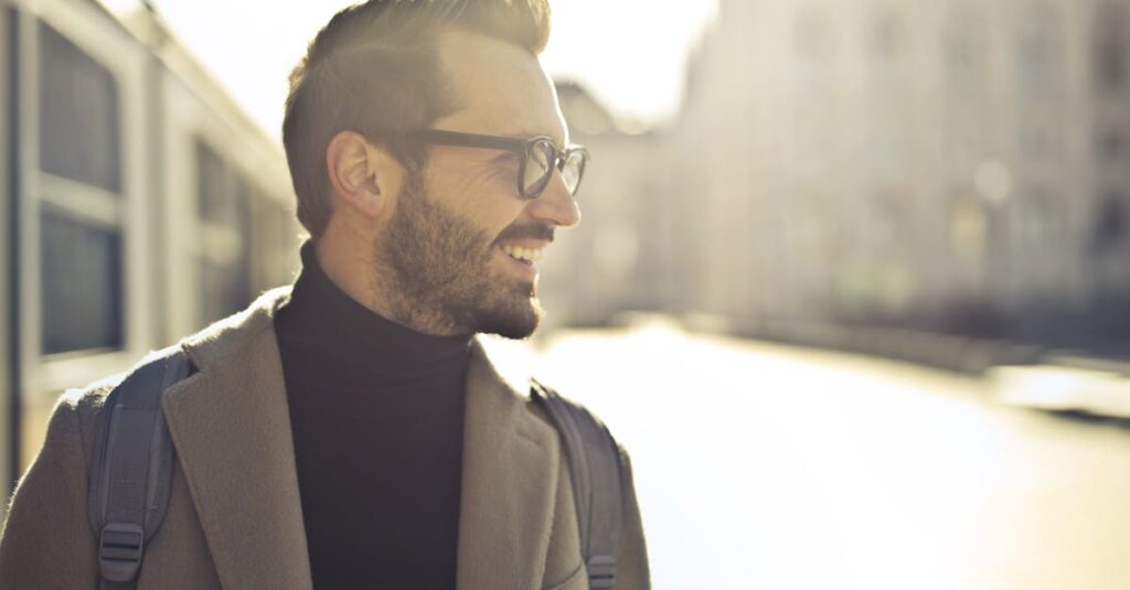 Smiling man with glasses and coat enjoying a sunny day in Budapest.