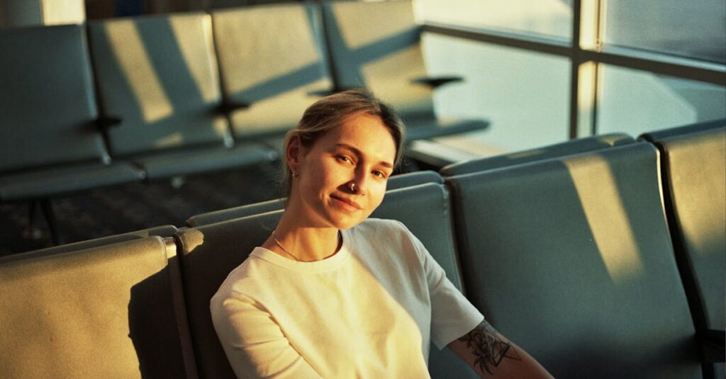 Smiling woman in an airport lounge seat, bathed in warm evening light.