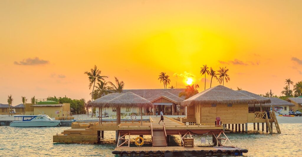 Beautiful sunset view at Kanuhura, Maldives with overwater bungalows and serene ocean surroundings.