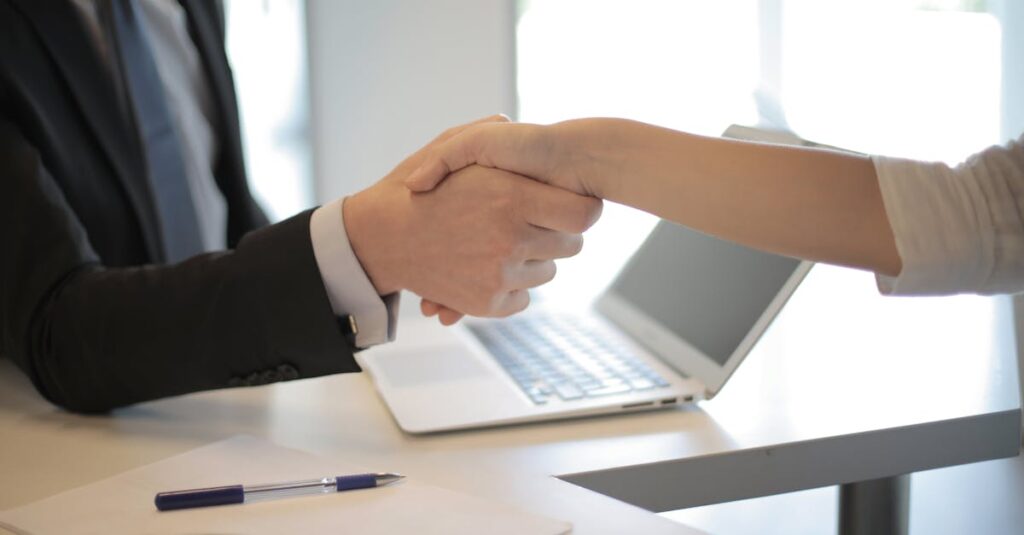 Close-up of a professional handshake over a laptop during a business meeting in an office.