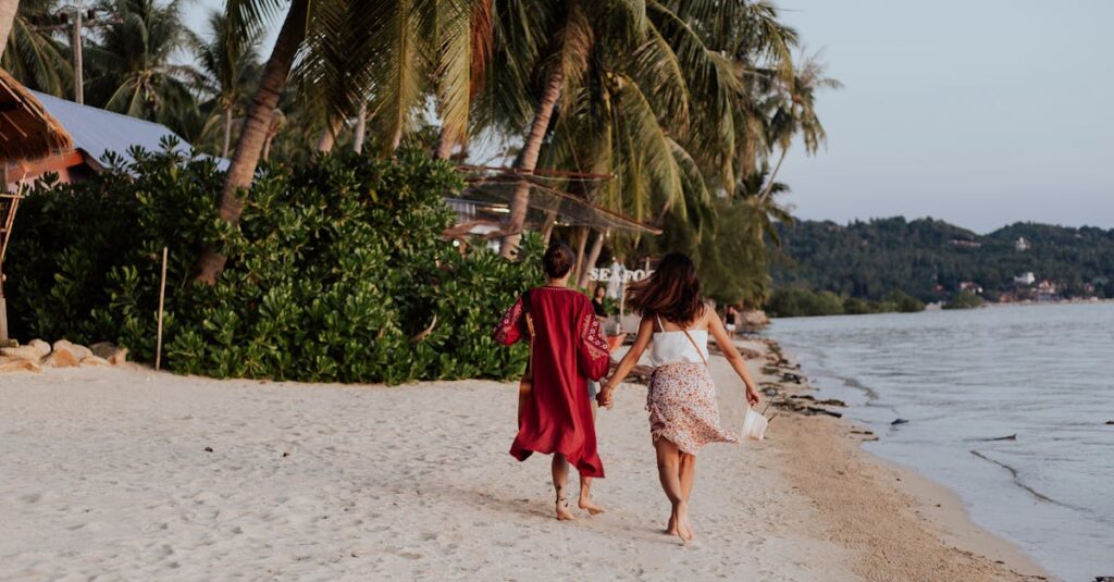 Two women holding hands and walking along a sandy tropical beach, enjoying their summer vacation.