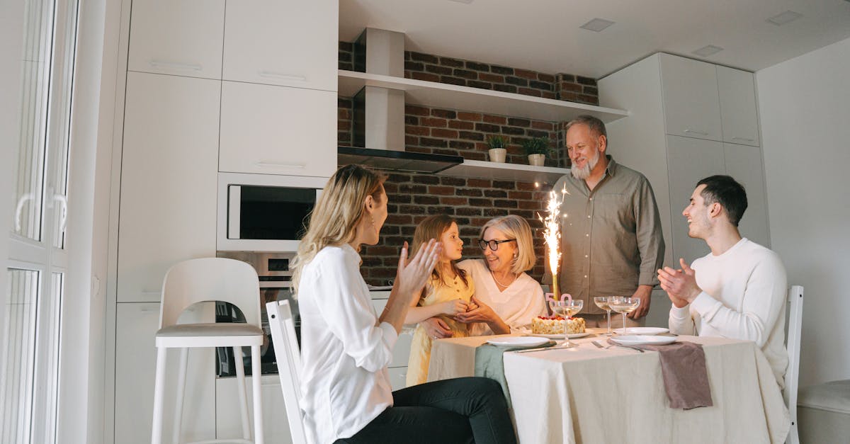 Joyful family gathering celebrating a birthday with a cake and sparkling candle in a cozy dining room.